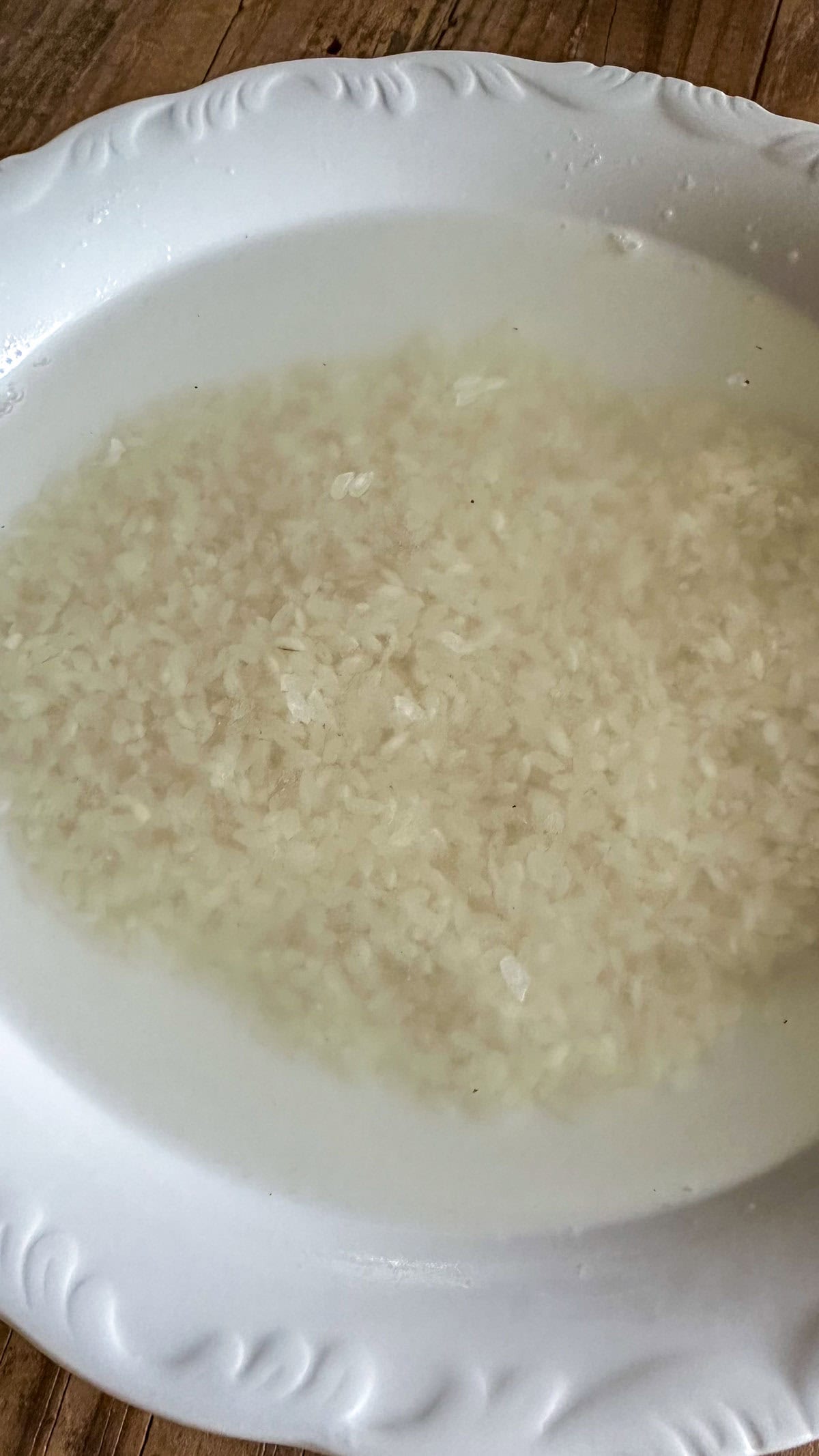 A bowl containing short grain rice soaking in water.