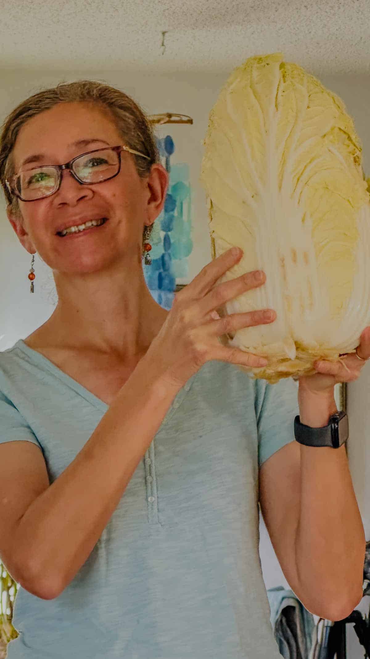 Grace author of ExploreCookEat holding a large napa cabbage.
