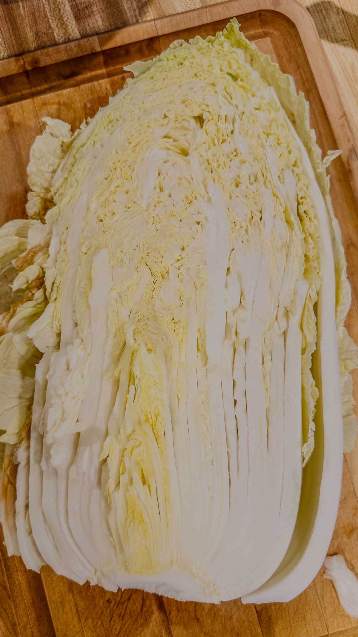 Half of a napa cabbage on a wooden cutting board.