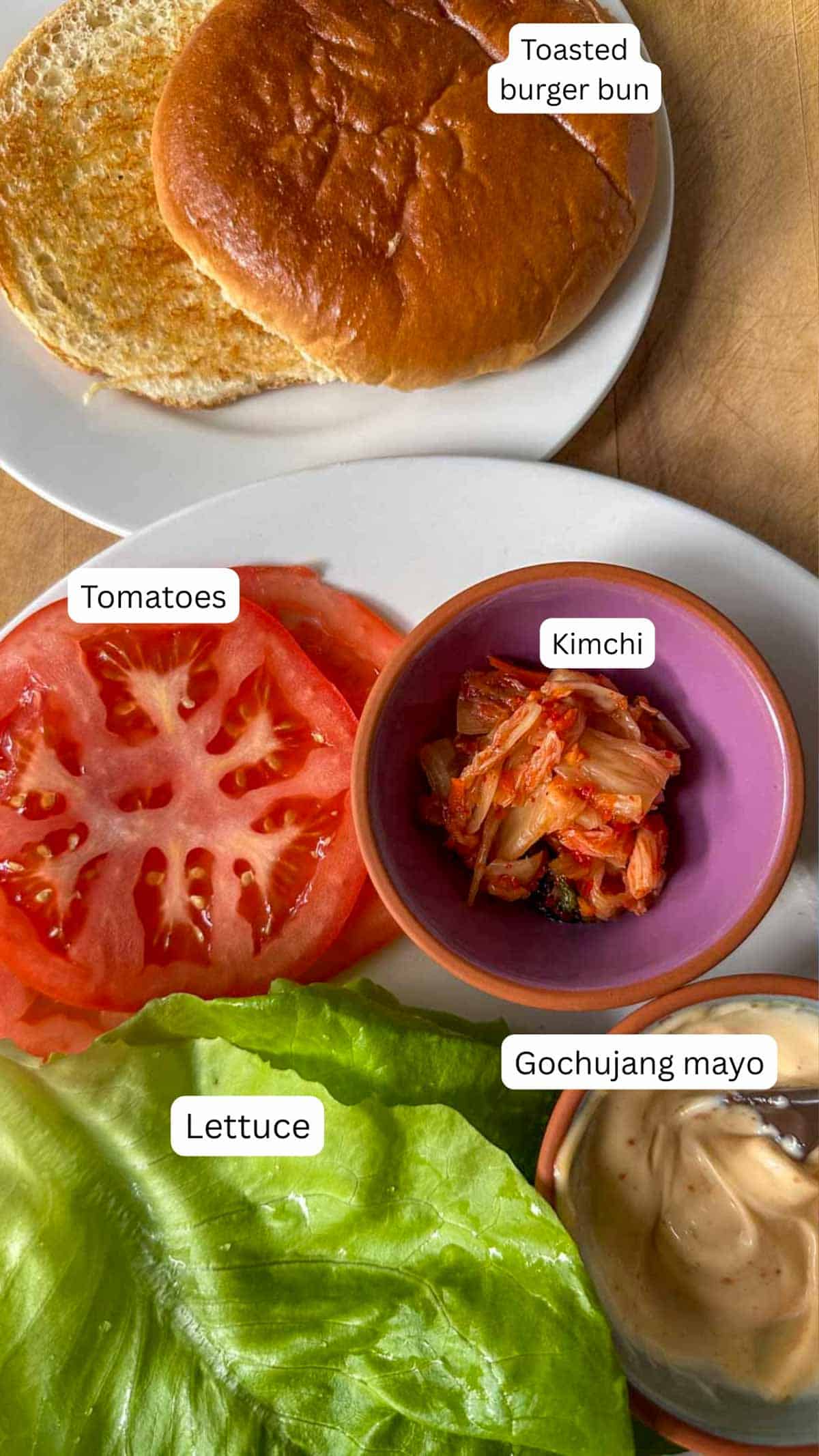 Ingredients for bulgogi burger toppings including tomatoes, kimchi, lettuce, gochujang mayo, and a toasted burger bun.