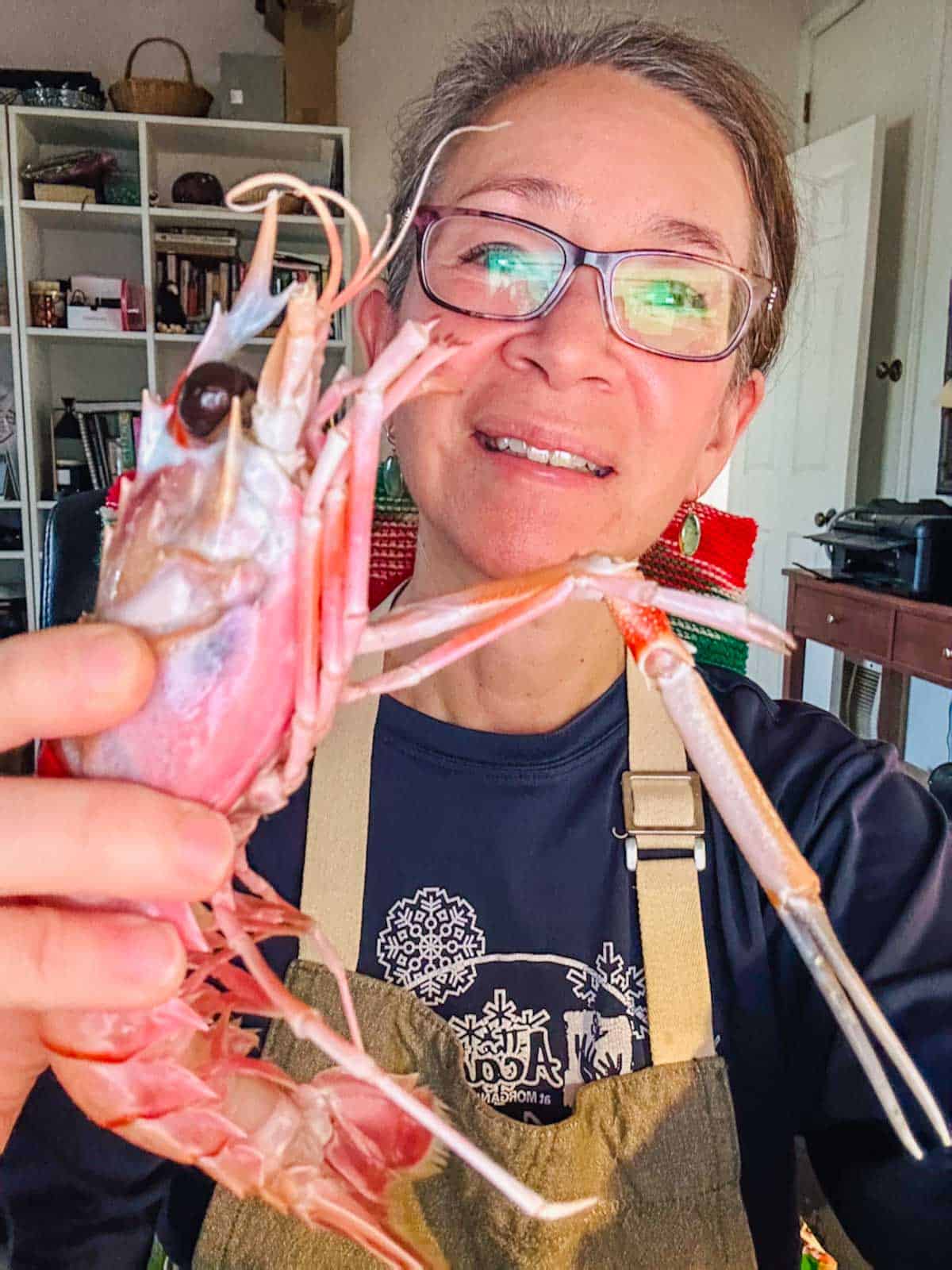 A woman with glasses holding a New Zealand scampi.