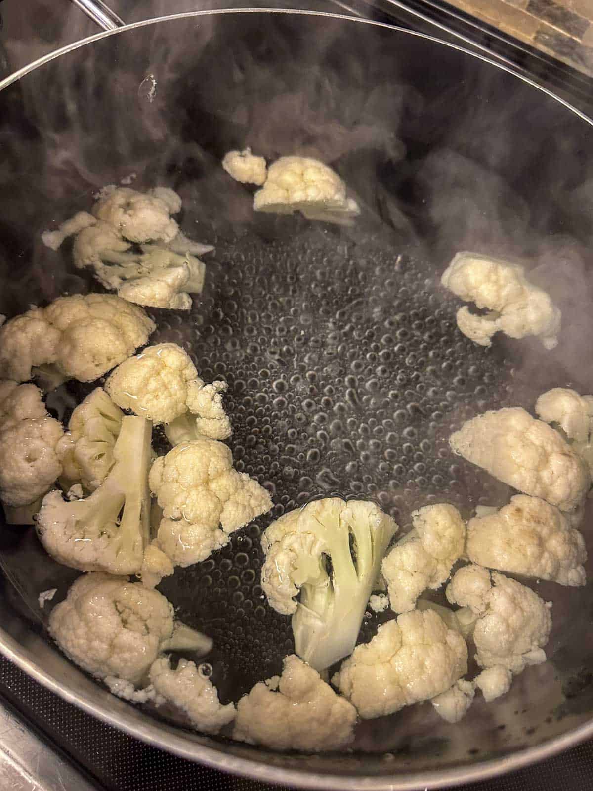A pot containing cauliflower florets in boiling water.