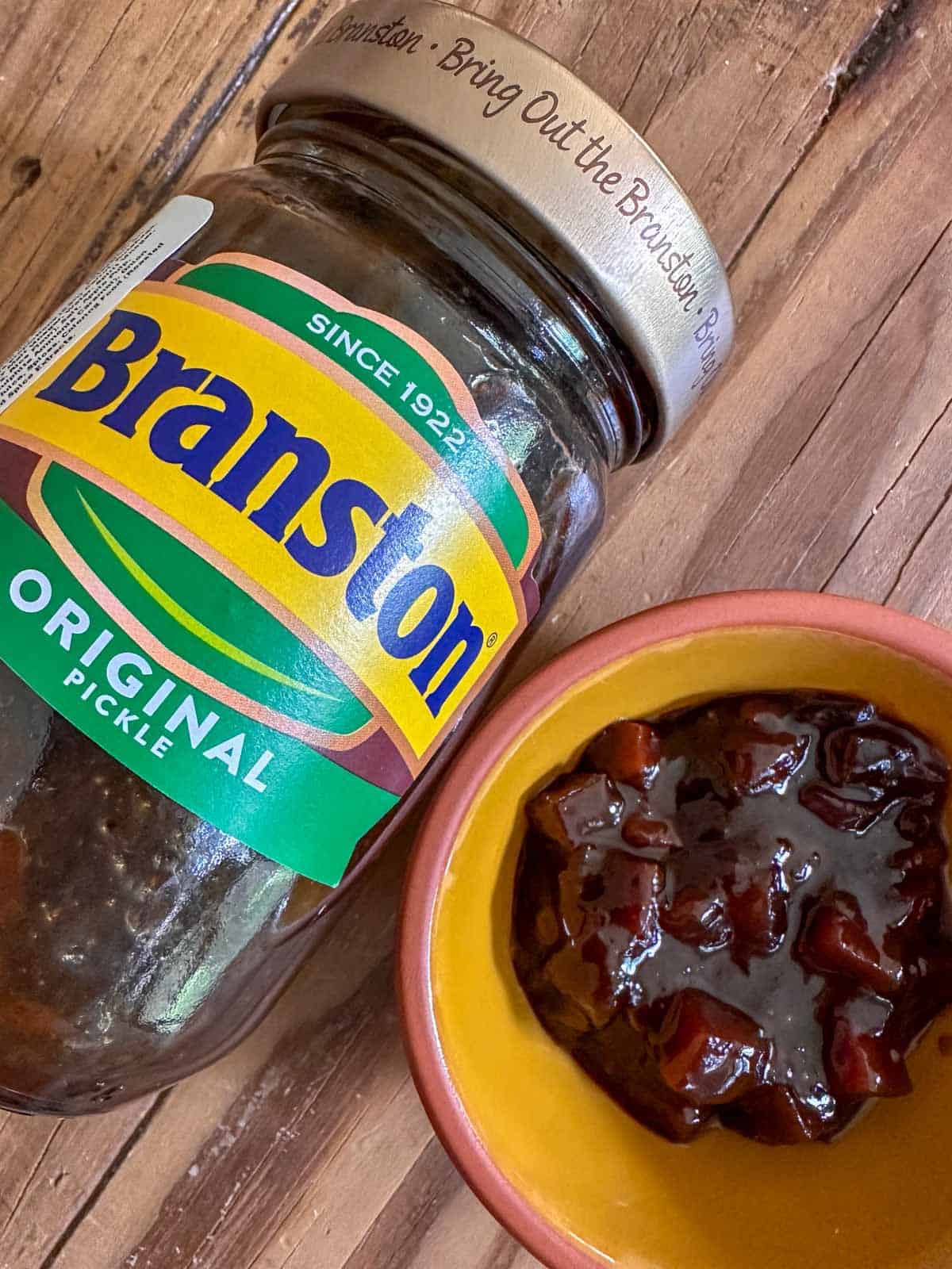 A jar of Branston pickle next to a small bowl with Branston pickle.