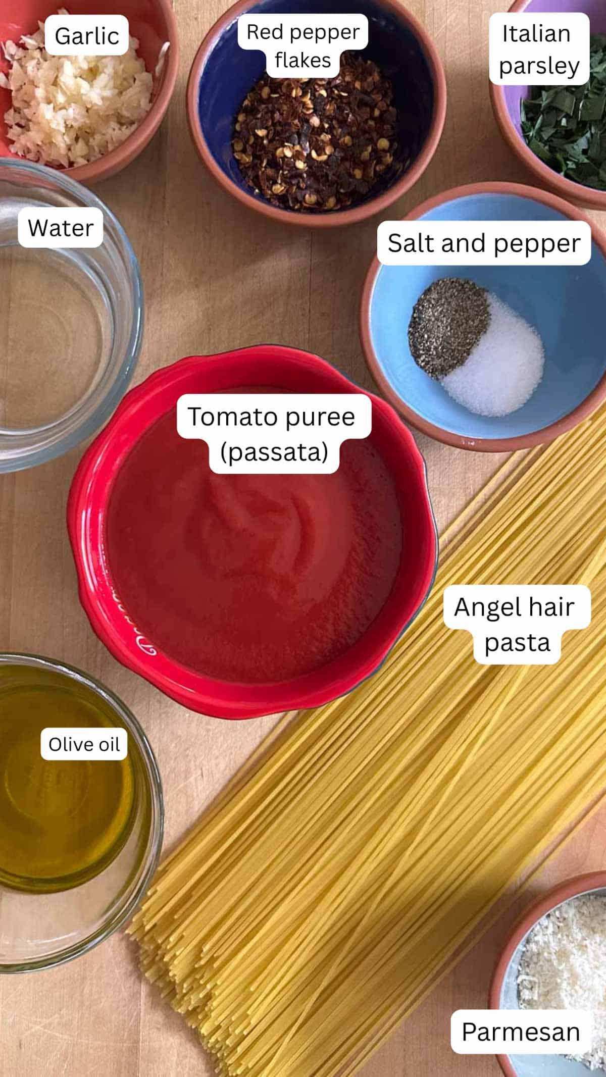 Ingredients for Spicy Angel Hair Pasta With Tomato Puree including pasta, Parmesan, olive oil, tomato puree, salt and pepper, water, garlic, red pepper flakes and Italian parsley.