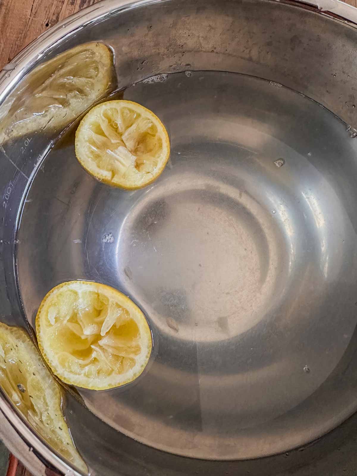 A bowl containing lemon water and two lemon halves.