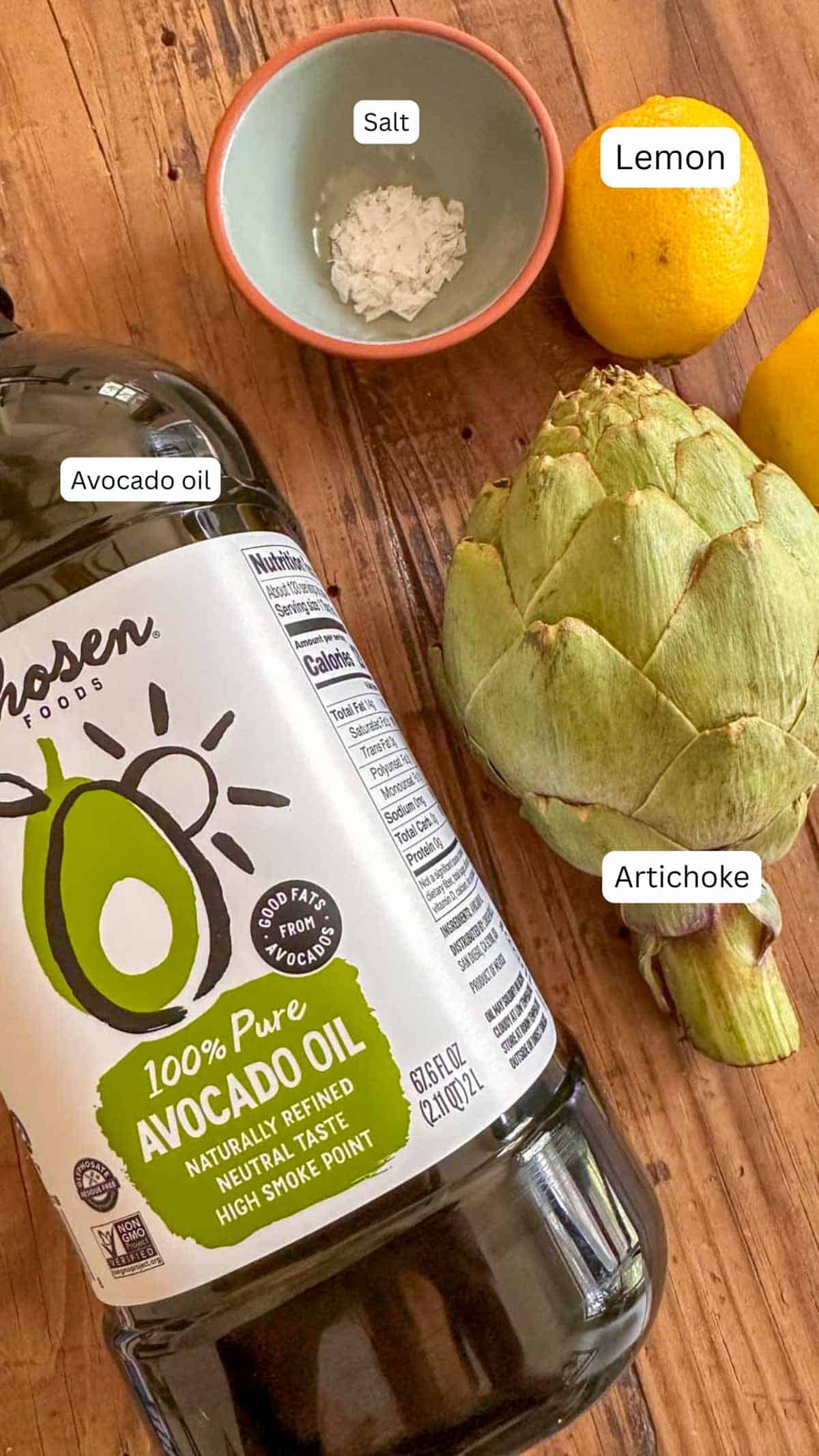 Fresh artichoke, lemon, avocado oil, salt in a bowl for cooking.